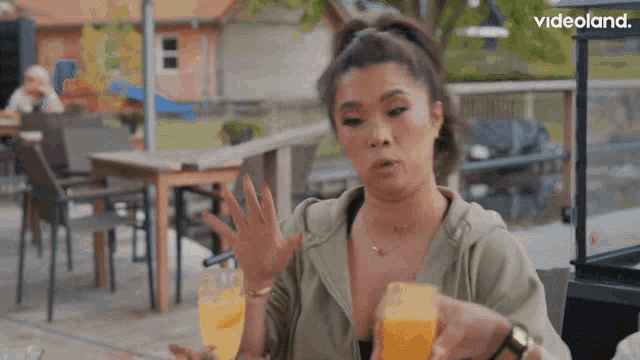 a woman is sitting at a table with a glass of orange juice in front of a videoland ad