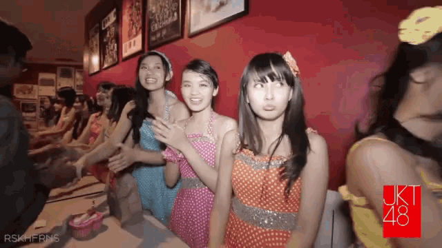a group of girls are standing in front of a red wall with a sign that says uki 48
