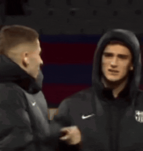 a man wearing a nike jacket with a hood is talking to another man