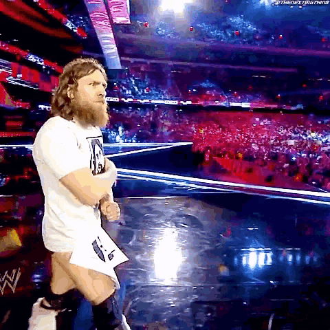 a bearded man in a white shirt is walking on a stage in front of a crowd ..