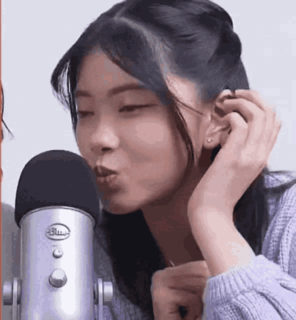 a woman is singing into a blue yeti microphone while wearing earrings .