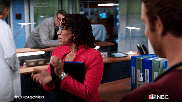 a woman in a red jacket is talking to a man in an office with the hashtag #chicagomed on the bottom