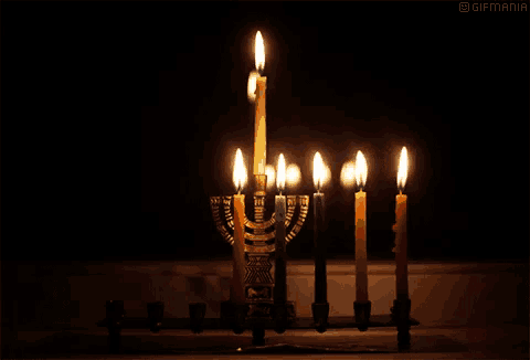 a menorah with many lit candles and the word gifmania at the top