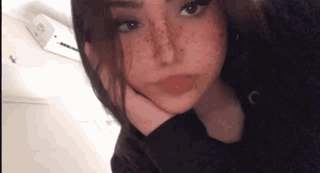 a girl with freckles on her face is taking a selfie .