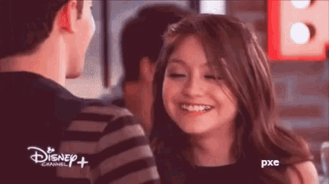a man and a woman are looking at each other and smiling in a disney channel ad .