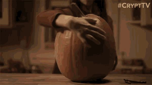 a woman is carving a pumpkin with a bat face on it