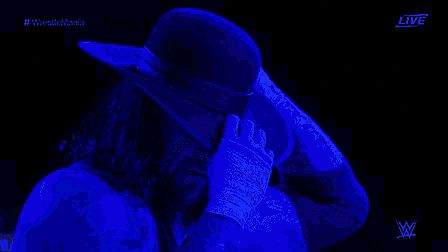 a man wearing a hat and gloves is standing in a dark room