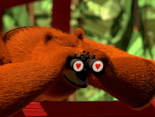 a teddy bear is looking through binoculars with hearts in the eyes