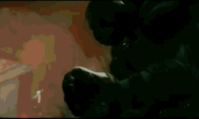 a man in a gas mask is standing in a dark room holding a gun .