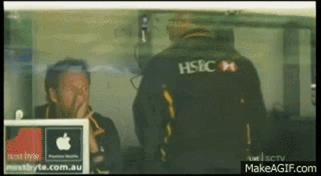 a man wearing a hsbc jacket looks at another man