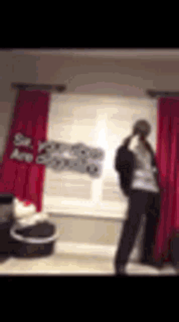 a blurry picture of a person standing in front of a window with pink curtains .