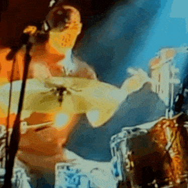 a man playing drums in front of a microphone in a blurry photo