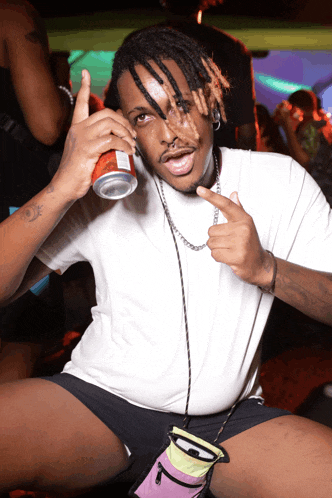 a man in a white shirt holds up a can of soda