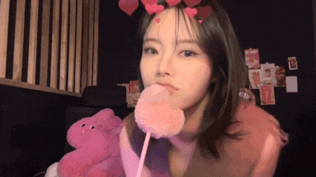 a woman with hearts on her head is holding a pink lollipop .