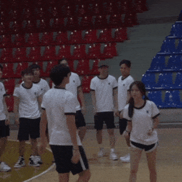 a girl in shorts stands in front of a group of boys