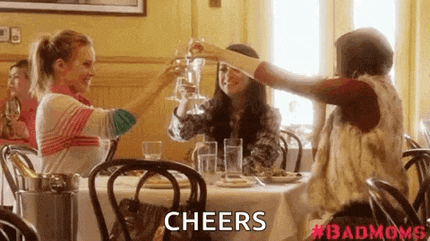 a group of women are sitting at a table toasting with wine glasses in a restaurant .