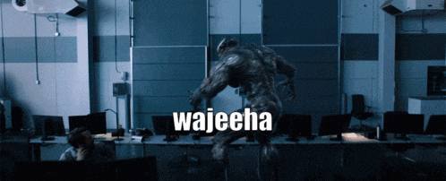 a man sits at a desk in front of a wall that says wajecha