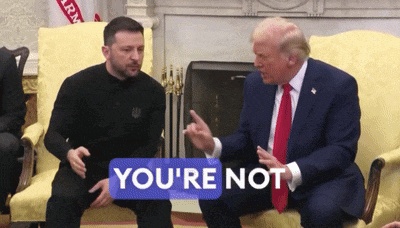 two men are sitting on a couch and one of them has a sticker that says you 're not