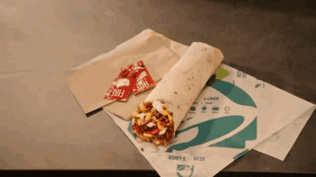 two packets of hot sauce sit next to a taco bell burrito