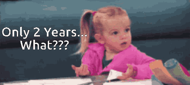 a little girl in a pink jacket is sitting at a table with the words only 2 years what written above her