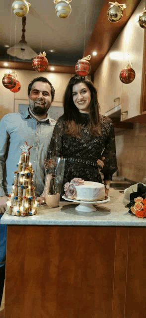 a man and a woman are posing for a picture in front of a cake