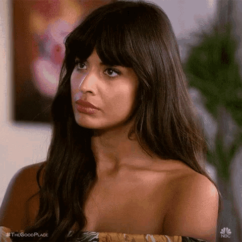 a woman with long hair and bangs is wearing a strapless top and looking at the camera .