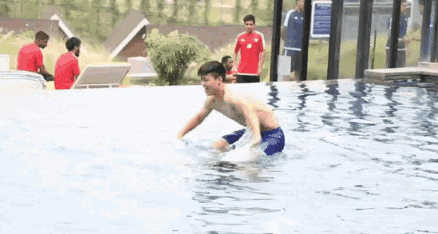 a shirtless man is swimming in a pool