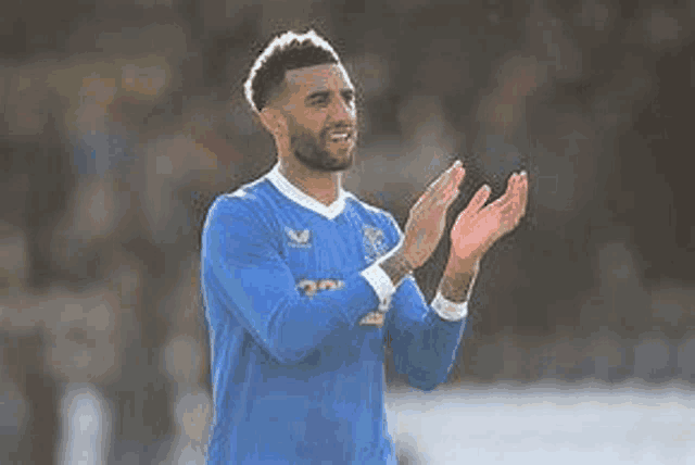a soccer player in a blue shirt is clapping his hands .