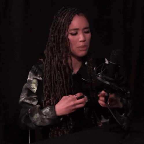 a young woman with dreadlocks is speaking into a microphone