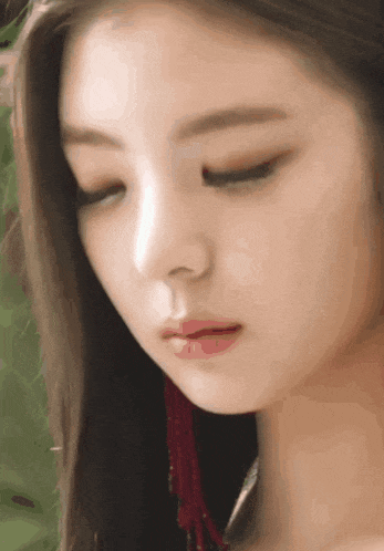 a close up of a woman 's face with her eyes closed and red earrings