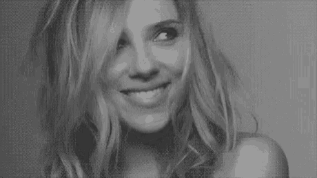 it is a black and white photo of a woman with long hair looking at the camera .