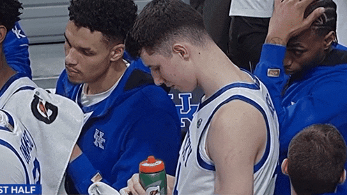 a group of basketball players are sitting in a huddle with a gatorade bottle