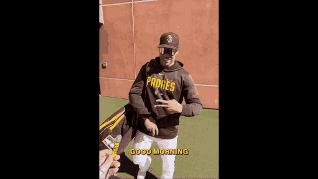 a man wearing a padres sweatshirt is shaking hands with another man