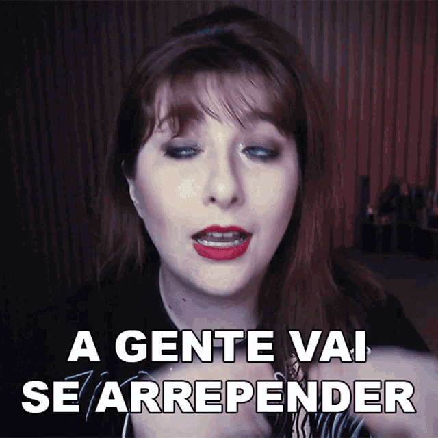 a woman says a gente vai se arrepender in front of a red curtain