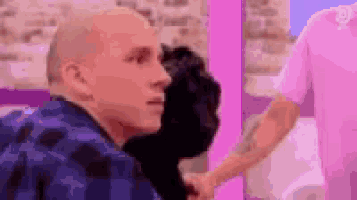 a bald man is shaking hands with a woman in a pink shirt .