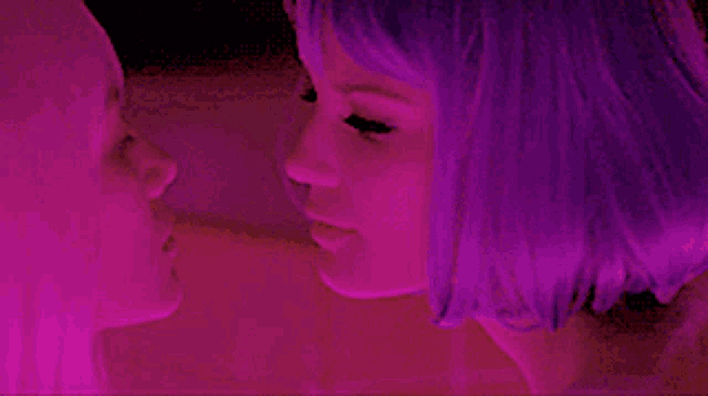 a woman with purple hair kisses another woman