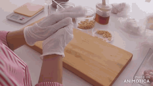 a person wearing white gloves is putting nuts on a wooden cutting board