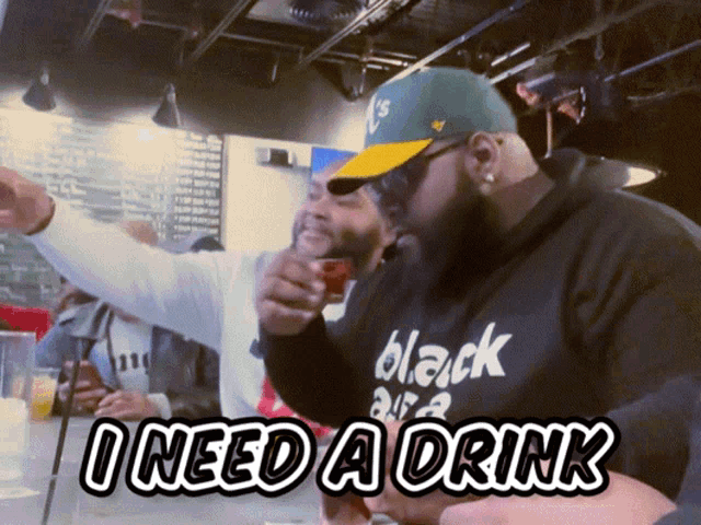 a man wearing a black shirt that says ' i need a drink ' on it