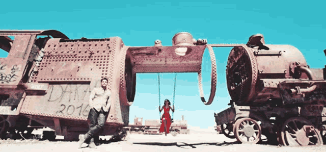 a man and a woman are standing in front of a train that has the year 2016 written on it