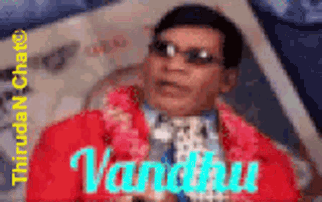 a man wearing sunglasses and a red jacket is holding a book titled vandhu