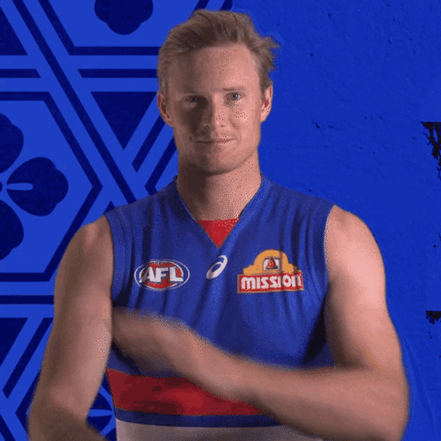 a man in a red white and blue striped shirt is crossing his arms in front of a blue background