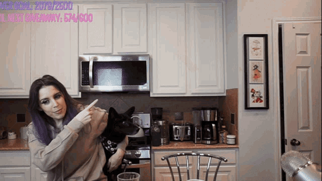 a woman with purple hair holds a black dog in front of a microwave and says her goal is 2070/2500