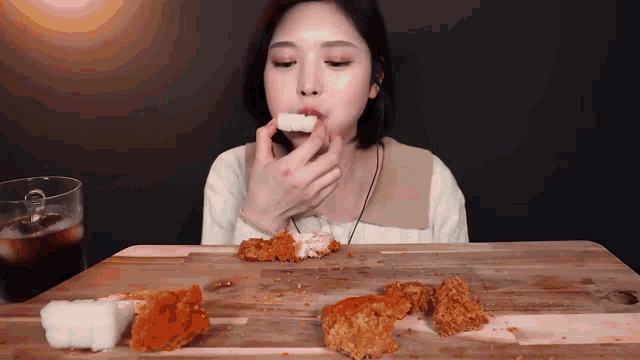 a woman is sitting at a table eating chicken