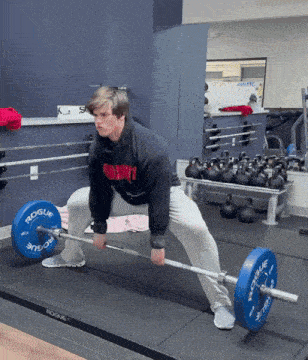 a man lifting a barbell in a gym with a rogue logo on the barbell