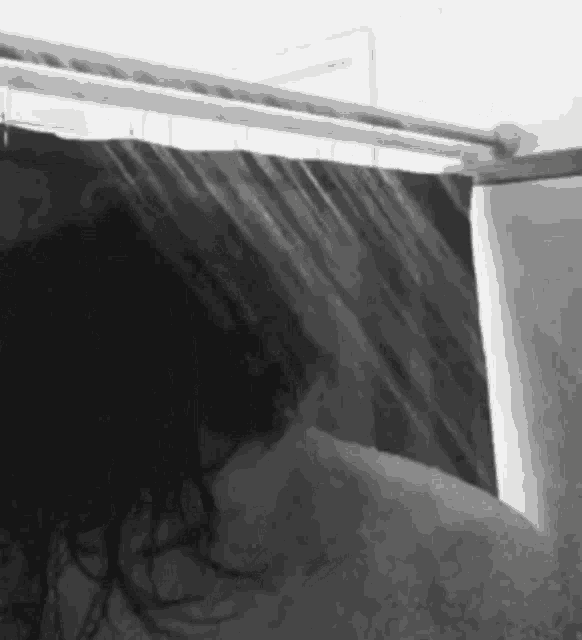 a woman is taking a shower with a shower curtain hanging over her head