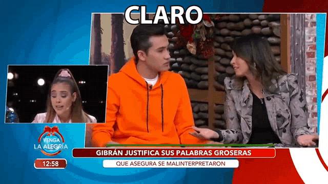 a man in an orange sweatshirt is talking to a woman on a television screen that says claro