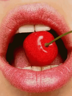 a close up of a woman 's lips with a cherry sticking out of it