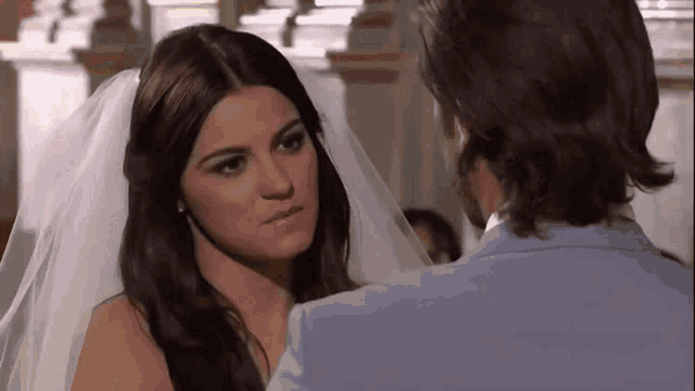 a bride and groom are looking at each other and the bride is wearing a white veil