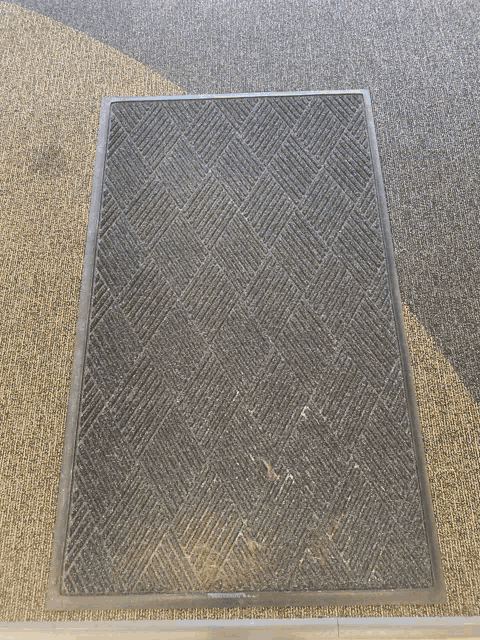 a black mat with a metal frame is on a carpeted floor