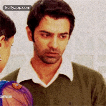 a man in a green sweater is looking at a woman in a blue dress .